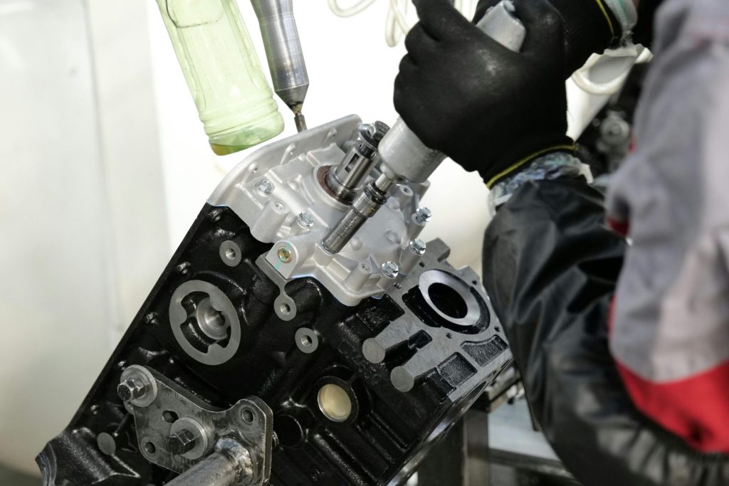 Skilled mechanic working on engine assembly with precision tools in factory setting.